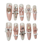 Blush Snow Bows long stiletto press-on nails in blush pink and white, featuring 3D ribbon bows, snowflake charms, fluffy pom-poms, pearls, and sparkling crystals. Winter holiday nail design by Poppy Nails.