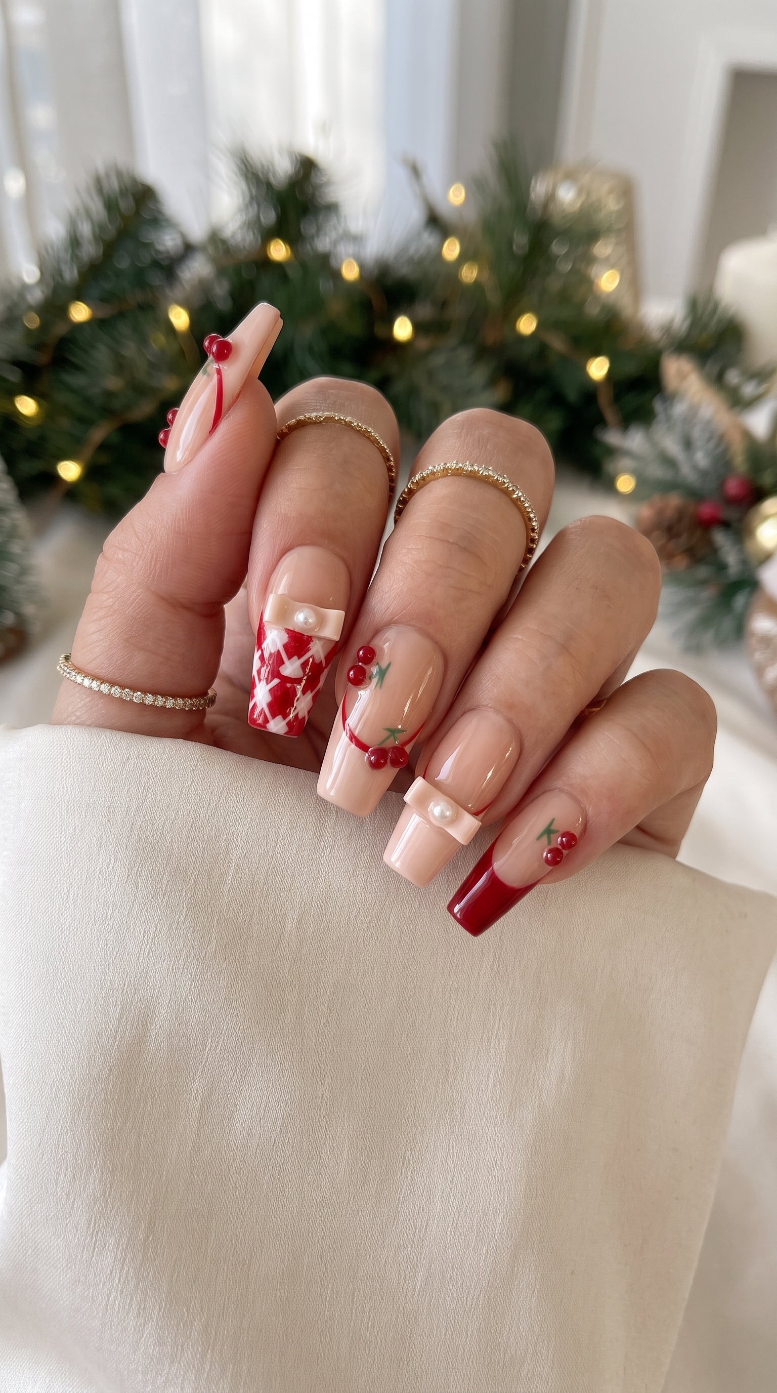 Cherry Ribbon Kiss red and nude pink press-on nails worn on hand, featuring long coffin nails with 3D cherries, pearl ribbon bows, plaid French tips, and sweet coquette nail art.