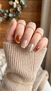 Cocoa & Twinkle short oval Christmas press-on nails worn on hand, featuring chocolate brown chrome, cream white nails, red polka dots, a glittery Christmas tree, and sparkling silver confetti.