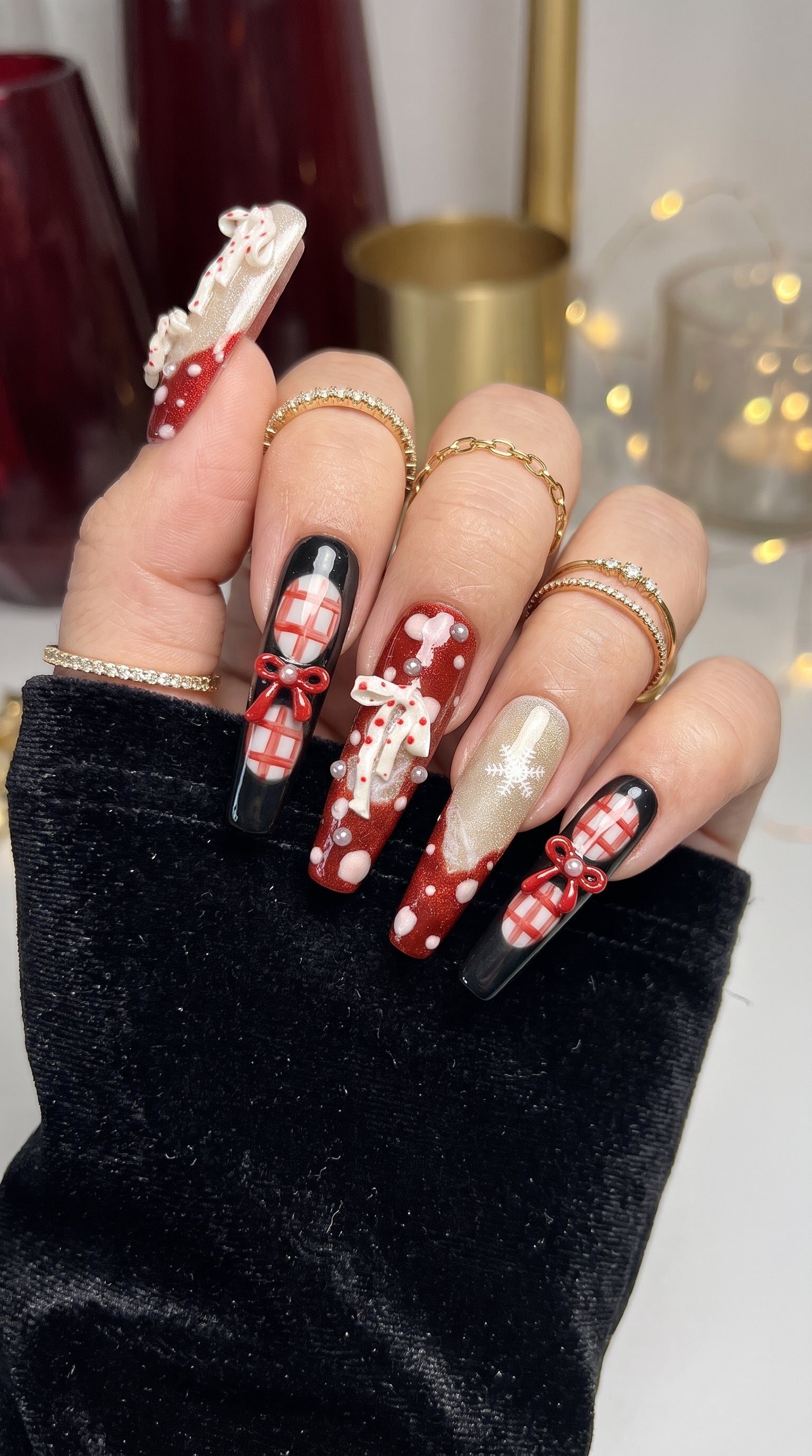 Midnight Candy Bows Christmas press-on nails worn on hand, featuring long coffin nails with red and black plaid designs, 3D candy canes, festive bows and sparkling snowflakes.