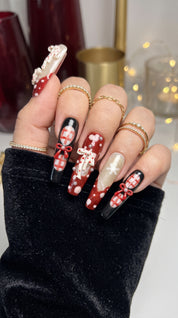 Midnight Candy Bows Christmas press-on nails worn on hand, featuring long coffin nails with red and black plaid designs, 3D candy canes, festive bows and sparkling snowflakes.