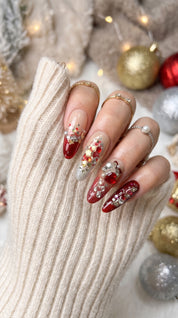 Ruby Teddy Treasures luxury press-on nails worn on hand, featuring long coffin nails with ruby red glitter, gold accents, 3D teddy bears, jeweled bows and pearl embellishments.